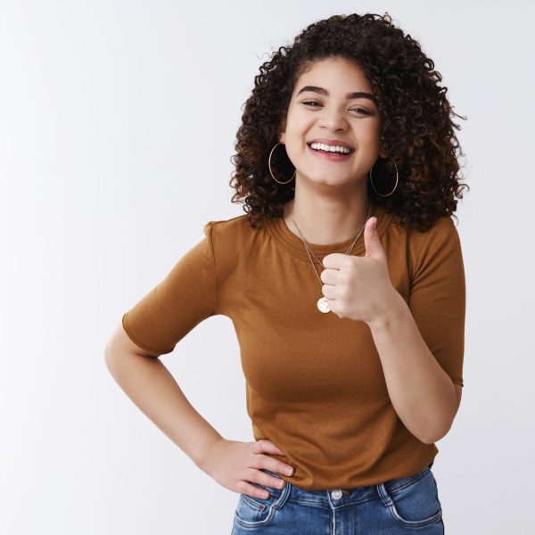 Good thanks. Happy charismatic laughing young attractive girl curly dark hair show thumb up smiling satisfied approve awesome great deal like cool choice picking outfit friend date, white background Programa de Beneficios