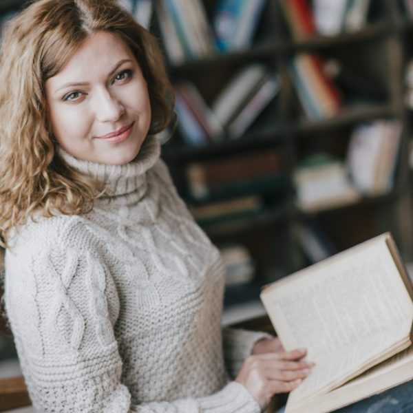 woman-with-book-near-blurred-bookcase Descuentos Comerciales